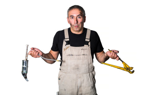A confused looking plumber in white overalls holding a pipe wrench and clamp.